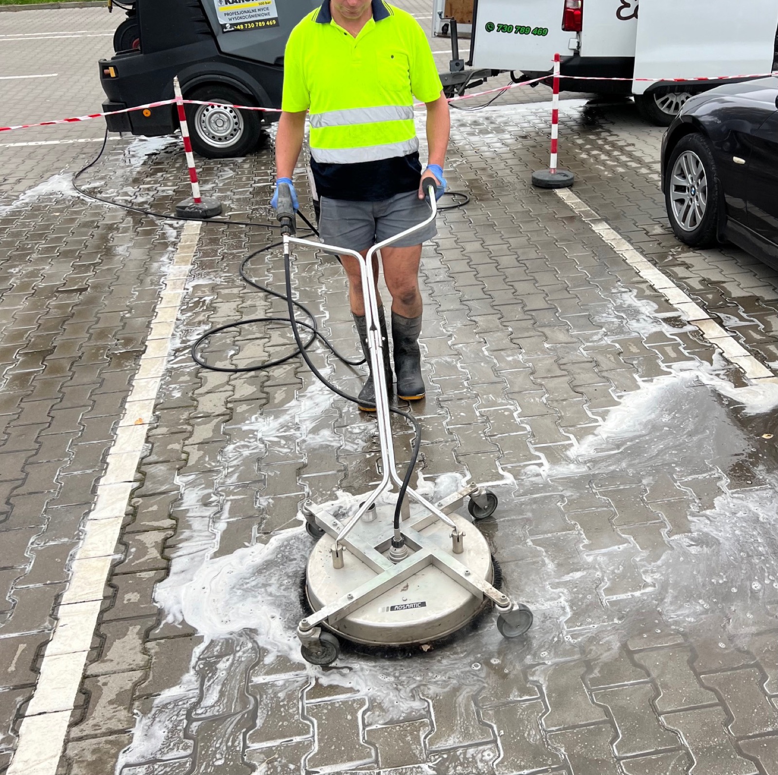 Usuwanie plam olejowych z kostki brukowej — pracownik ze szczotką T-racer